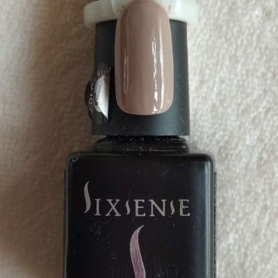 Frasco preto de gel para unhas SIXSENIE com amostra de cor castanho nude aplicada no topo.