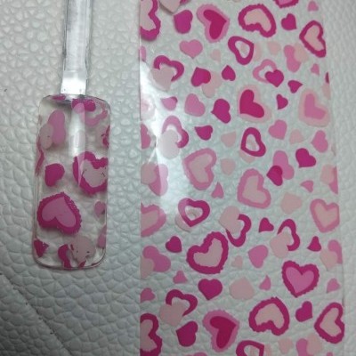 Película de unhas com padrão de corações em rosas e vermelho, parcial numa unha falsa