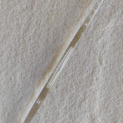 Pipeta de vidro transparente com graduação em branco sobre superfície branca texturizada