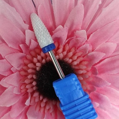 Broca de unha branca e azul sobre flor rosa artificial