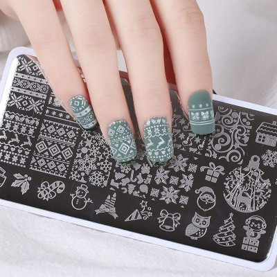 Unhas postiças verdes com desenhos natalinos brancos e placa metálica preta com desenhos para carimbos de unhas