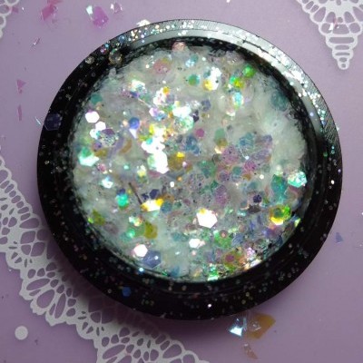 Pote preto com glitter holográfico prateado em fundo lilás com padrão rendado.