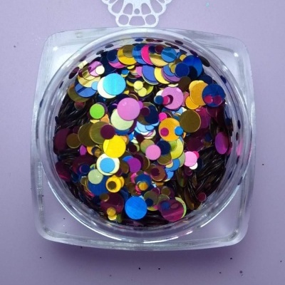 Pote quadrado transparente com confetes redondos coloridos sobre superfície lilás