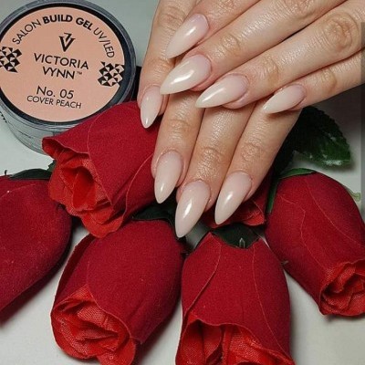 Unhas alongadas cor pêssego nude com pote de gel UV e flores vermelhas artificiais