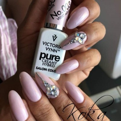 Frasco de verniz Victoria Vynn com unhas decoradas em rosa claro e pedrarias brilhantes