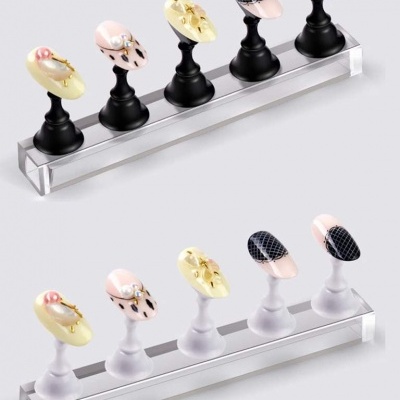 Exposição de unhas postiças decoradas em suportes em duas fileiras sobre base transparente.