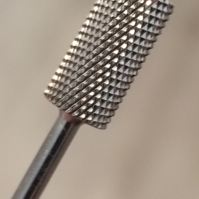 Broca cilíndrica de metal prateado com textura de pequenos dentes em relevo