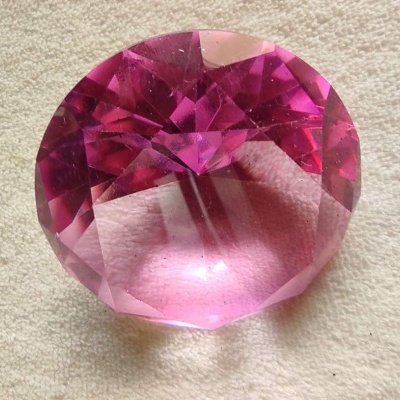 Pedra preciosa rosa facetada sobre tecido claro