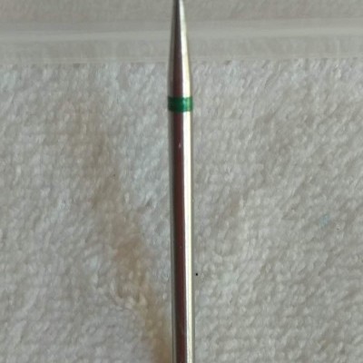 Broca metálica cilíndrica com ponta esférica e detalhe verde sobre fundo branco texturado.