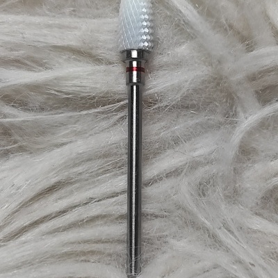 Broca para unhas branca com haste metálica num fundo felpudo branco