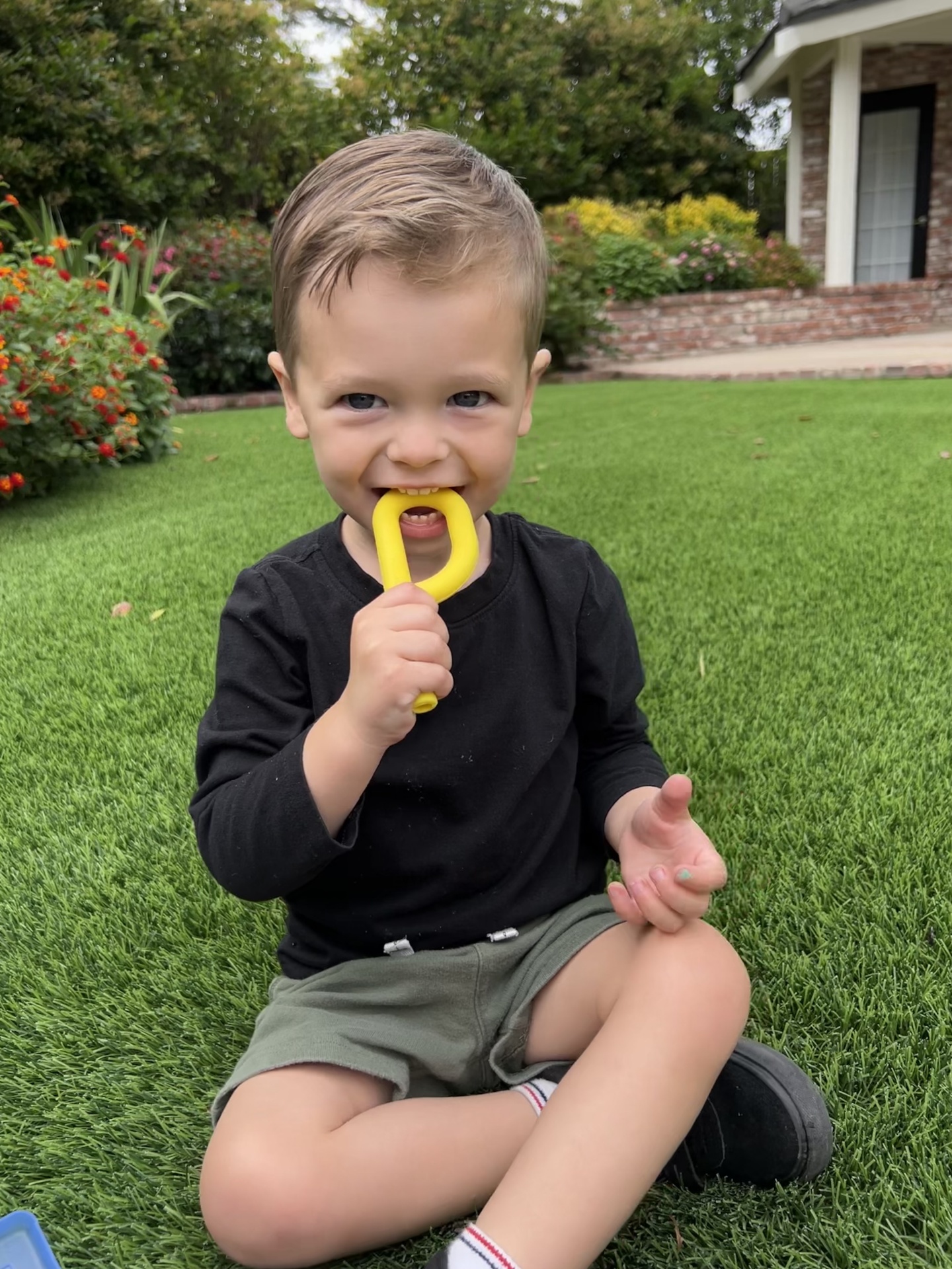 Mordedor ARK's Grabber® P Tube (oco e liso) Criança sentada na relva com mordedor amarelo