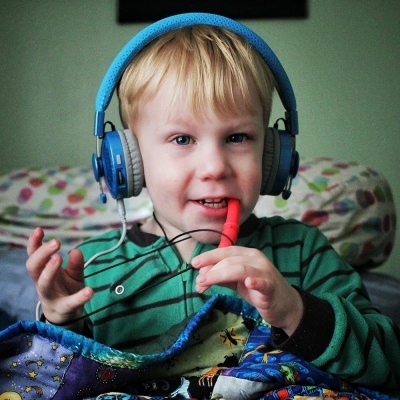 Criança com headphones azuis e apito vermelho