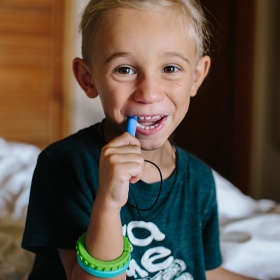 Menino loiro com apito azul e t-shirt azul escura em quarto