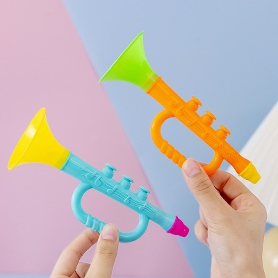 Dois trompetes de brinquedo coloridos em mãos contra fundo rosa e azul.
