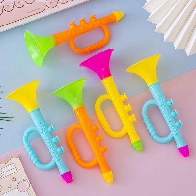 Trompetes de brinquedo coloridos em plástico sobre mesa azul e rosa