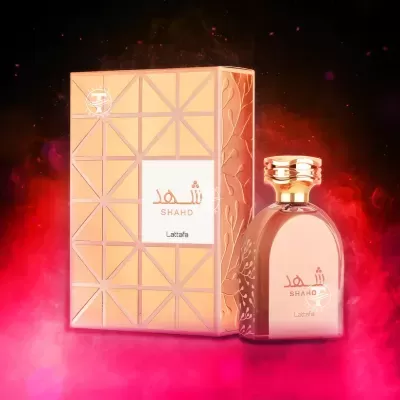 Frasco de perfume rosa e dourado com caixa correspondente embalada em fundo vermelho esfumaçado