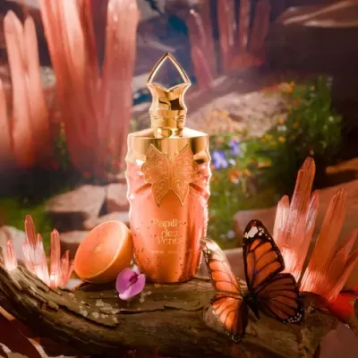 Frasco de perfume pêssego com borboleta dourada e tampo dourado em tronco com cristais e borboleta