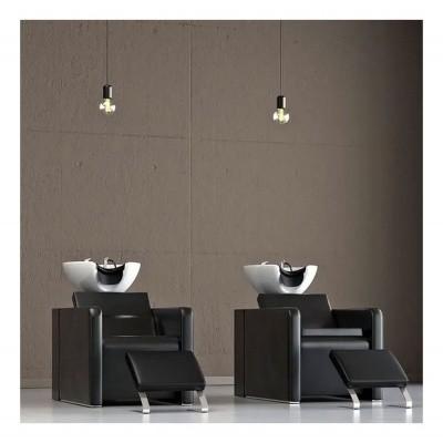 Duas cadeiras pretas para lavagem de cabelo com pias brancas e luminárias penduradas