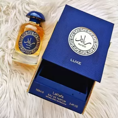 Perfume RA'ED LUXE com caixa azul aberta sobre superfície branca macia
