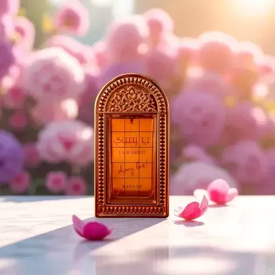 Frasco de perfume âmbar decorativo com texto YA HABIBTI e pétalas de flores cor-de-rosa