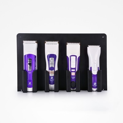 Quatro máquinas de cortar cabelo eléctricas em suporte de parede preto