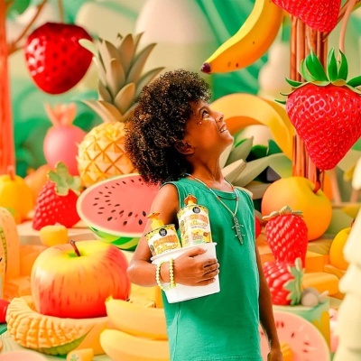 Criança perto de frutas artificiais grandes em cenário colorido