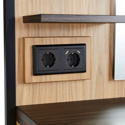 Tomada dupla embutida em moldura de madeira clara num painel de madeira clara com superfície escura ao lado