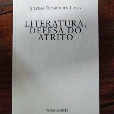 Livro branco com texto preto sobre madeira escura
