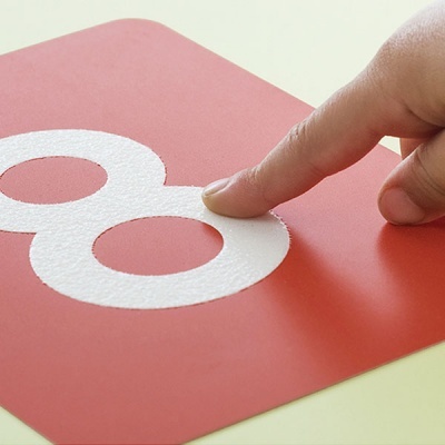 Placa vermelha com número 8 branco em relevo e dedo a tocar