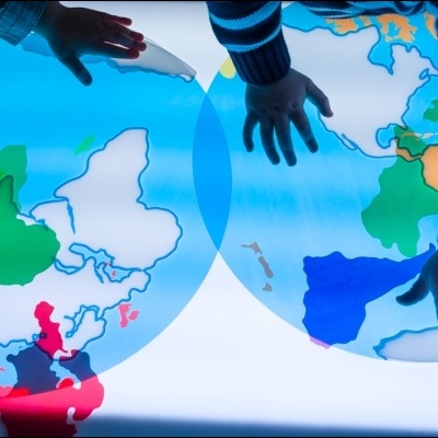 Mapa-múndi colorido iluminado com mãos de crianças a tocar