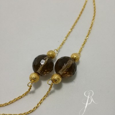 Colar dourado com pendentes esféricos castanhos escuros e textura detalhada