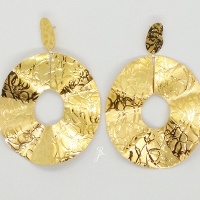 Brincos ovais dourados com textura martelada sobre fundo branco