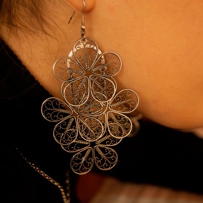 Brinco pendente em metal prateado com várias flores entrelaçadas e detalhes filigranados