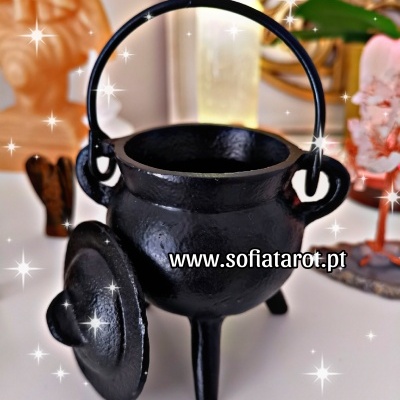 Caldeirão de ferro preto com tampa ao lado sobre superfície branca e fundo desfocado