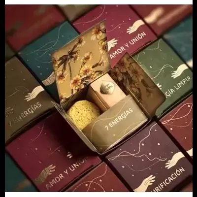 Caixas coloridas com texto em espanhol e design de mãos, uma caixa aberta mostra esponja e produto pequeno.