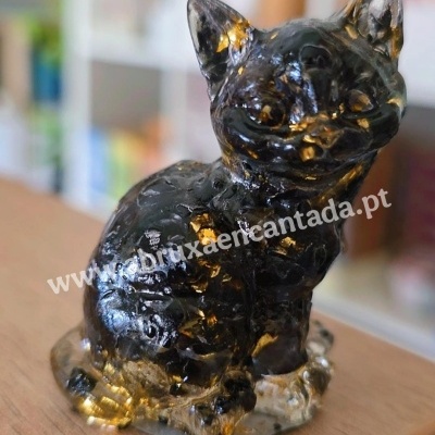 Estatueta de gato translúcido preto e dourado sobre superfície de madeira