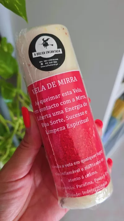 Vela de mirra creme e vermelha com rótulo vermelho e logo de bruxa