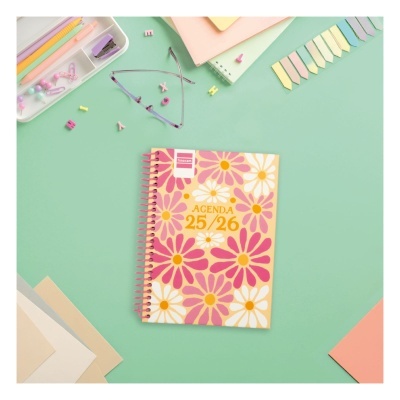 Agenda floral rosa e amarela sobre mesa verde com material de escritório