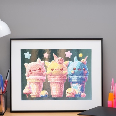 Quadro com ilustração de gelados cor-de-rosa, amarelo e azul com carinhas felizes, em moldura preta sobre secretária cinzenta.