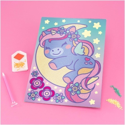 Quadro de unicórnio colorido sobre lua e estrelas com estojo de contas e aplicador, fundo rosa.