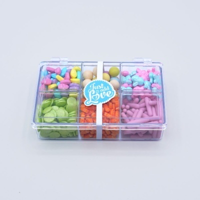 Caixa transparente com cápsulas e comprimidos coloridos e etiqueta 'Just add Love'.