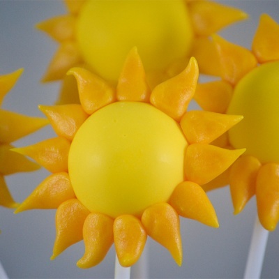 Pirulito em forma de sol amarelo com raios laranja