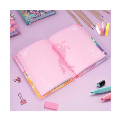 Caderno aberto com páginas cor-de-rosa e sombra de bailarina, rodeado por material escolar sobre superfície lilás