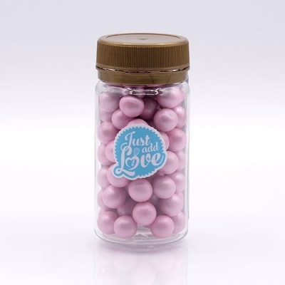 Frasco transparente com esferas cor-de-rosa e etiqueta 'Just add Love'