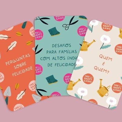 Três cartas coloridas com textos em português e ilustrações com o logo THE HAPPY GANG