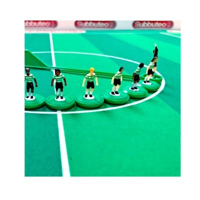 Jogadores de futebol de mesa Subbuteo com camisolas verdes e brancas numa mesa verde com linhas brancas