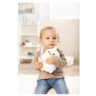 Criança sentada segurando brinquedo de pelúcia branco em forma de gato