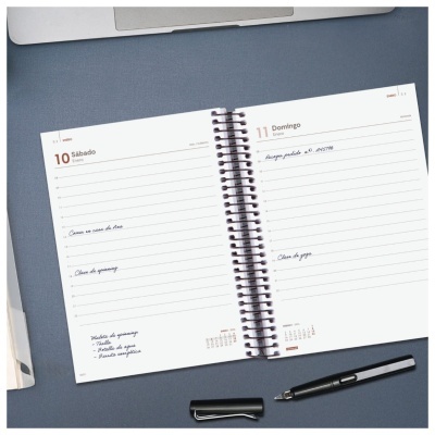 Agenda semanal aberta com anotações e caneta tinteiro preta sobre mesa azul