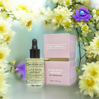 Elixir facial anti-idade NATURNUA em frasco de vidro com conta-gotas e caixa rosa junto a flores brancas e amarelas.