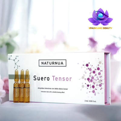 Embalagem branca de Suero Tensor NATURNUA com ampolas de vidro castanho claro e flores ao fundo